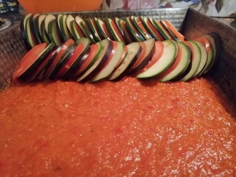 To liek dziļā cepešpannā, pa virsu pamīšus kārto ratatuja dārzeņu šķēles: baklažāns, cukīni zaļš, tomāts, cukīni dzeltens, baklažāns…
Autors: Laura Zaķe